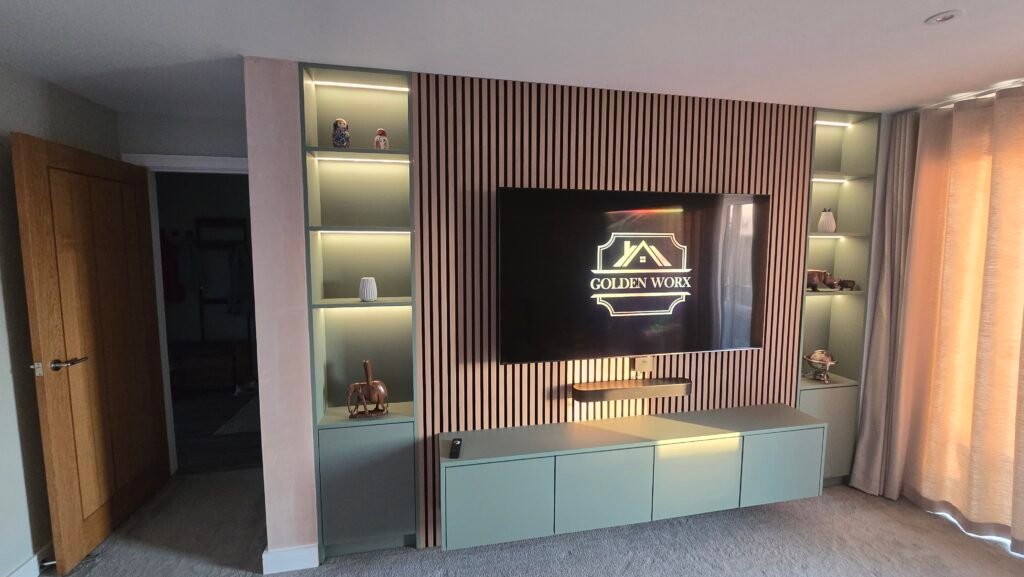 Entertainment wall with vertical wood slats, built-in shelves, and a mounted TV showing the 'GOLDEN WORX' logo; decorative objects on shelves.
